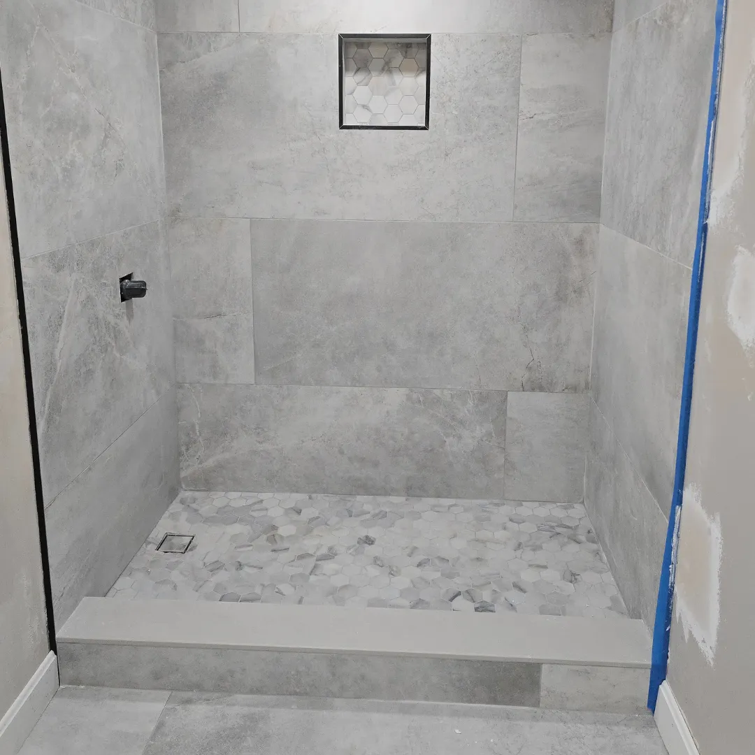 Large-format gray porcelain shower with hexagon mosaic floor and niche by Link Services Pro in Millbury, MA