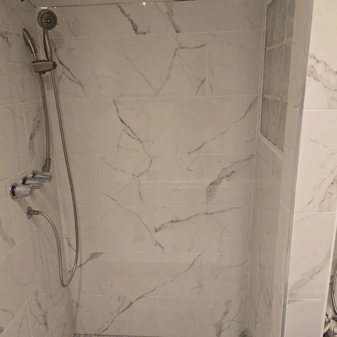 White Carrara marble shower walls with handheld fixture by Link Services Pro in Worcester, MA