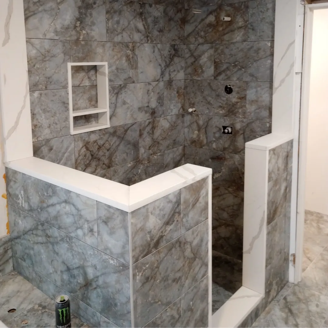 Gray marble-look tile shower walls with custom curb and niche by Link Services Pro in Holden, MA