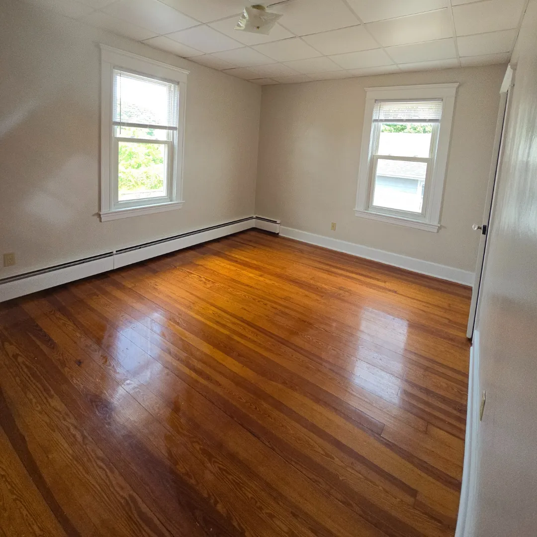 Refinished red oak hardwood floor in sunlit bedroom by Link Services Pro in Holden, MA