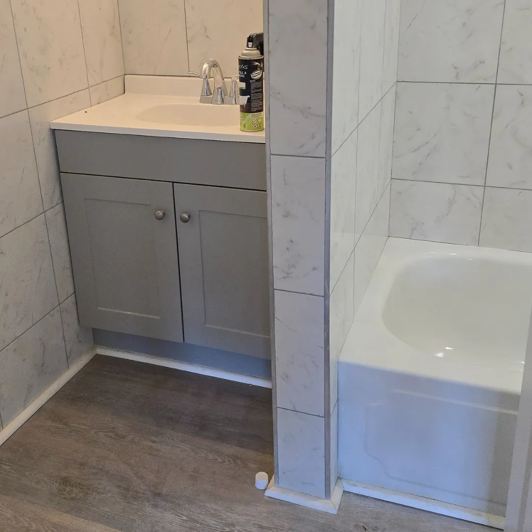Half bath with gray shaker vanity and marble-look porcelain wall tile by Link Services Pro in Westborough, MA