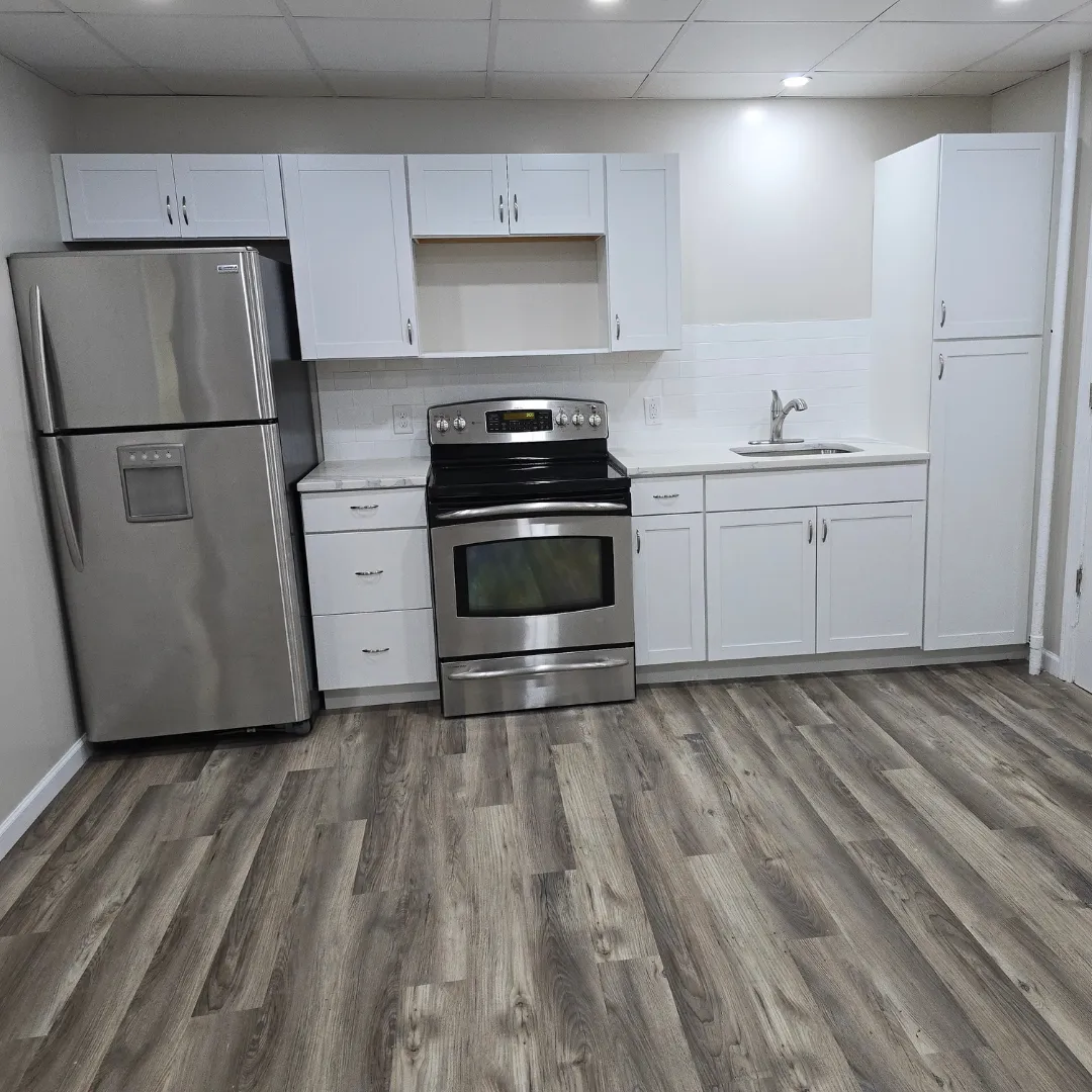 Compact kitchen with white shaker cabinets, granite counter and vinyl plank floor by Link Services Pro in Millbury, MA