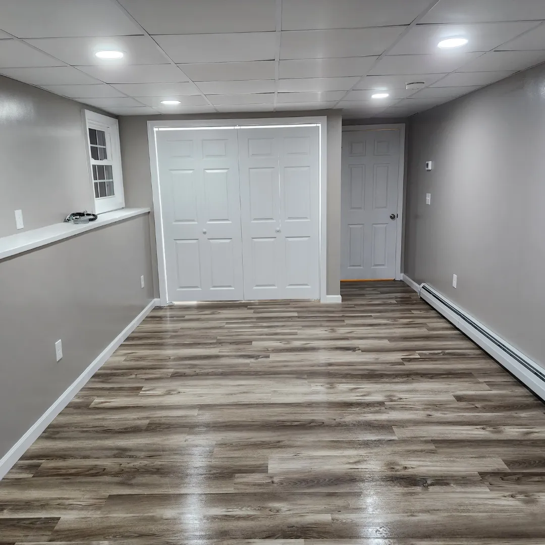 Finished basement with gray vinyl plank flooring and recessed lighting by Link Services Pro in Shrewsbury, MA