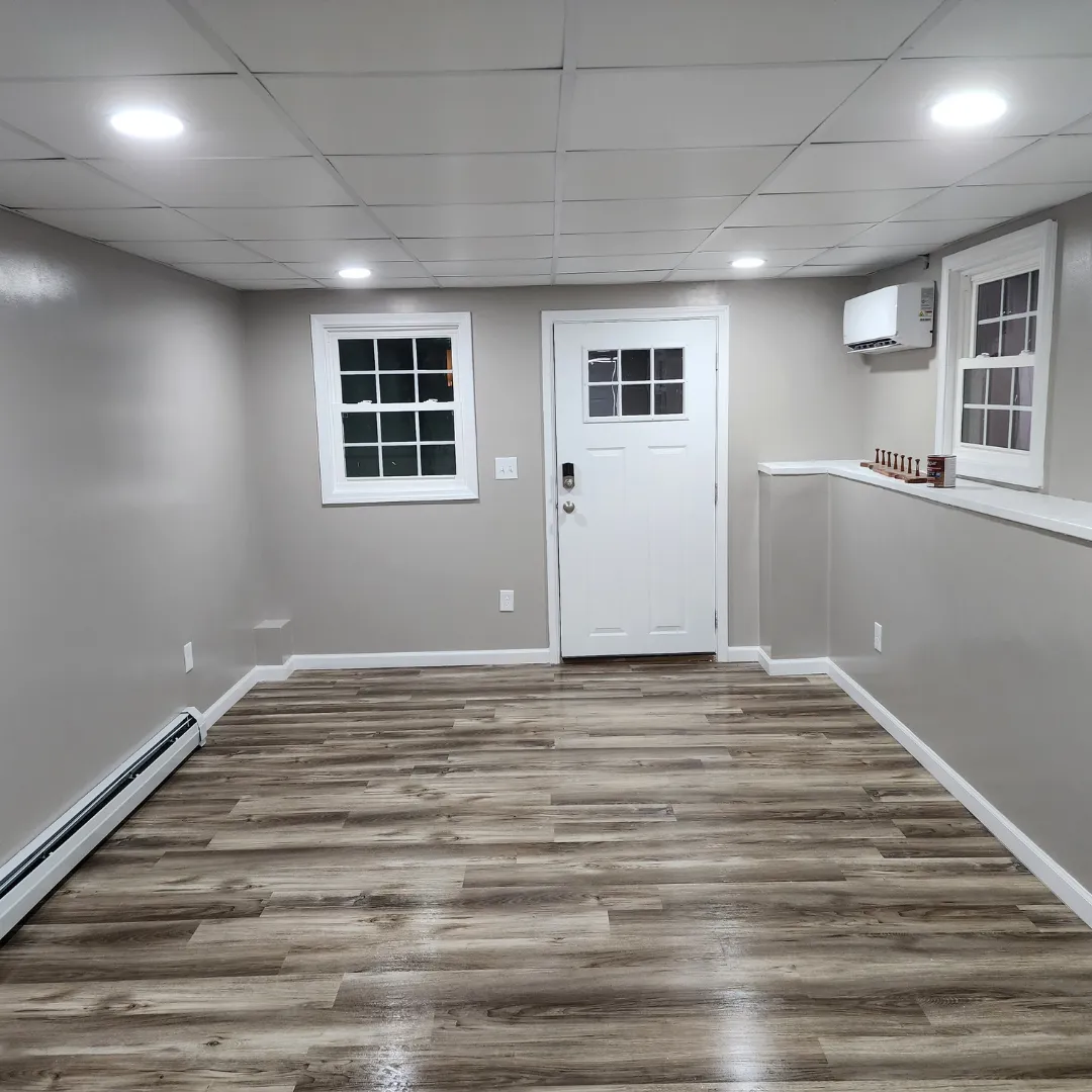 Finished basement entry with gray vinyl plank flooring and mini-split by Link Services Pro in Westborough, MA
