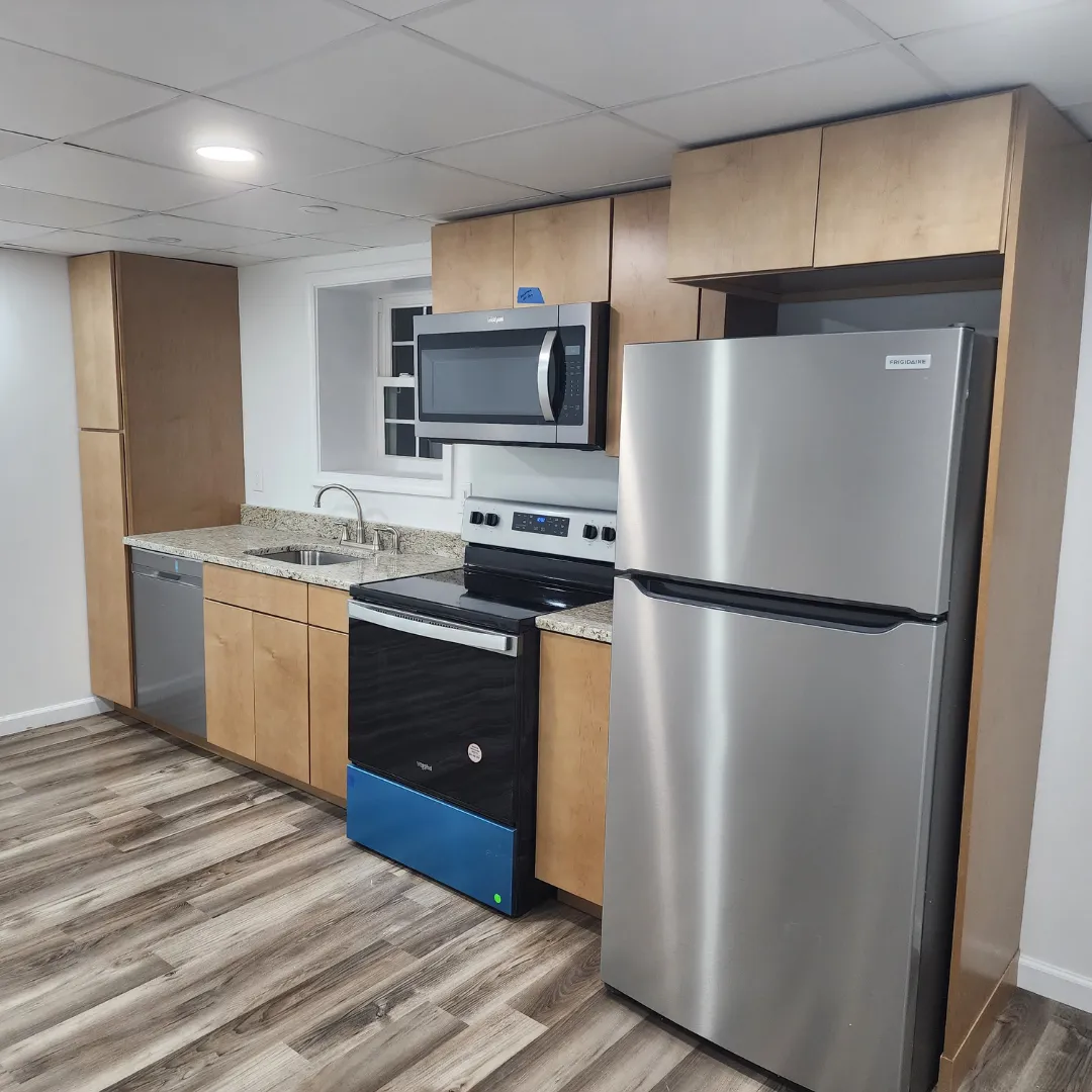 Basement kitchenette with natural wood cabinets and stainless appliances by Link Services Pro in Holden, MA