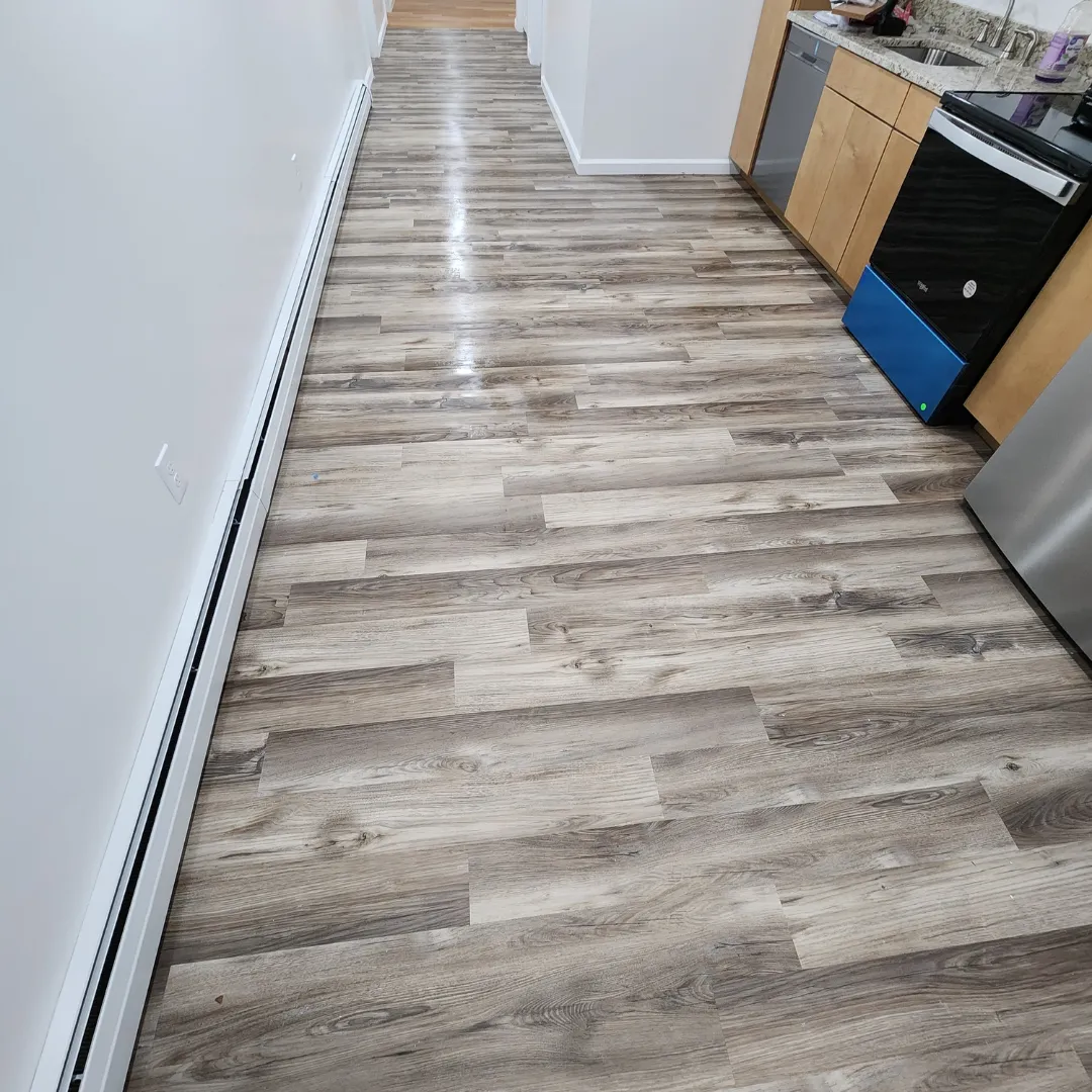 Wide hallway with weathered gray vinyl plank flooring and granite counter by Link Services Pro in Millbury, MA