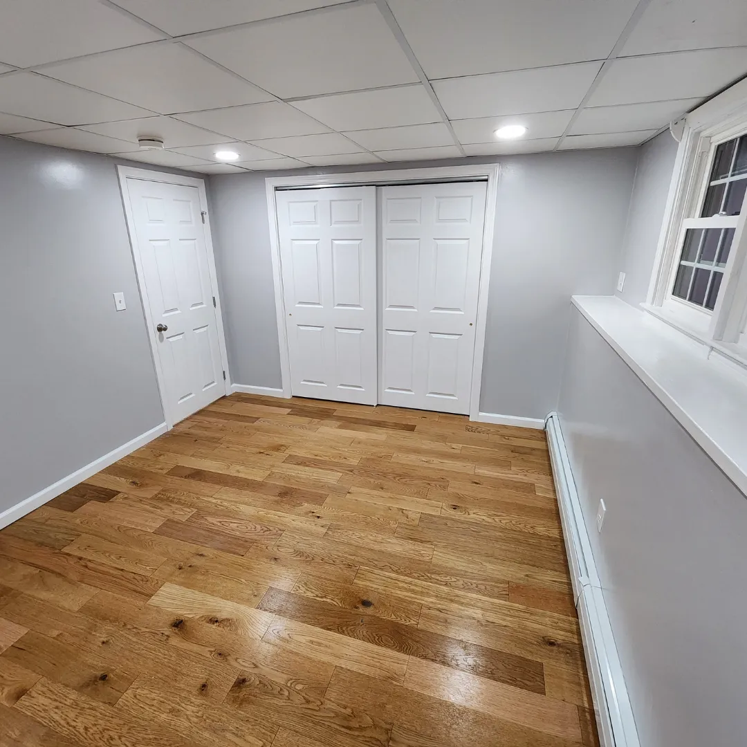 Refinished natural oak hardwood flooring in finished basement room by Link Services Pro in Auburn, MA