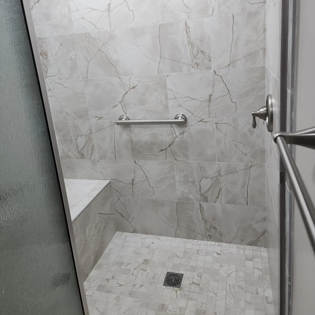 Marble-look porcelain shower with mosaic floor and built-in bench seat by Link Services Pro in Holden, MA