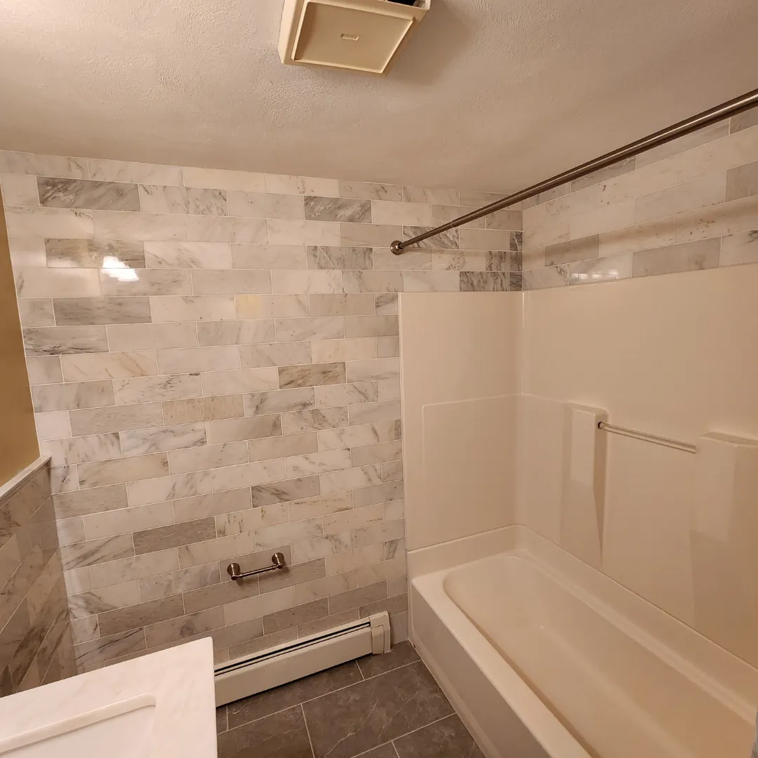 Bathtub-shower combo with marble subway tile surround by Link Services Pro in Auburn, MA