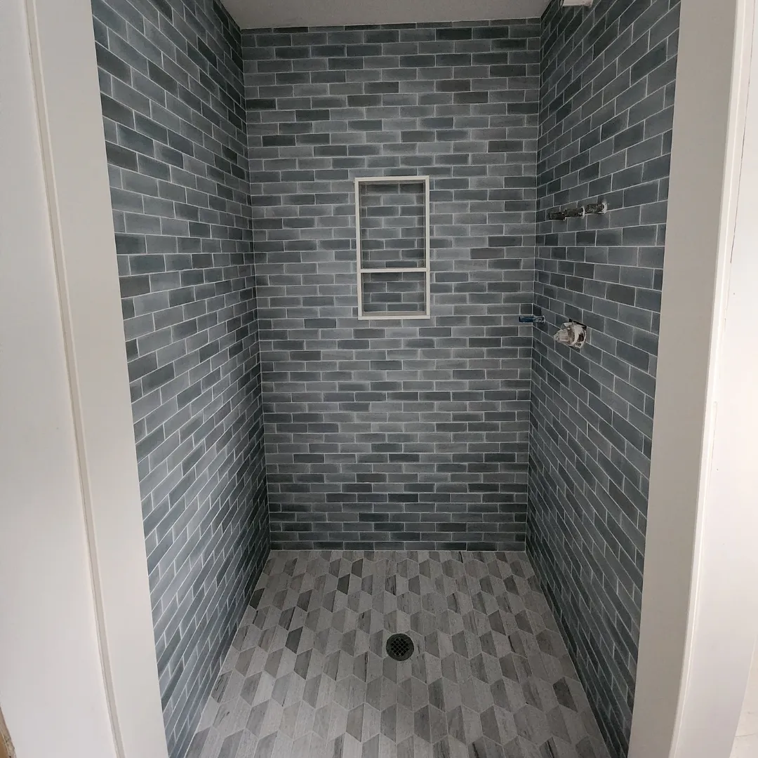 Walk-in shower with blue-gray subway tile walls and hexagon mosaic floor by Link Services Pro in Westborough, MA