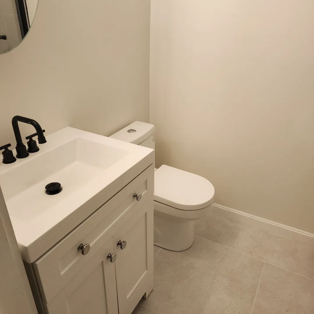 Compact powder room with white shaker vanity and matte black faucet by Link Services Pro in Holden, MA