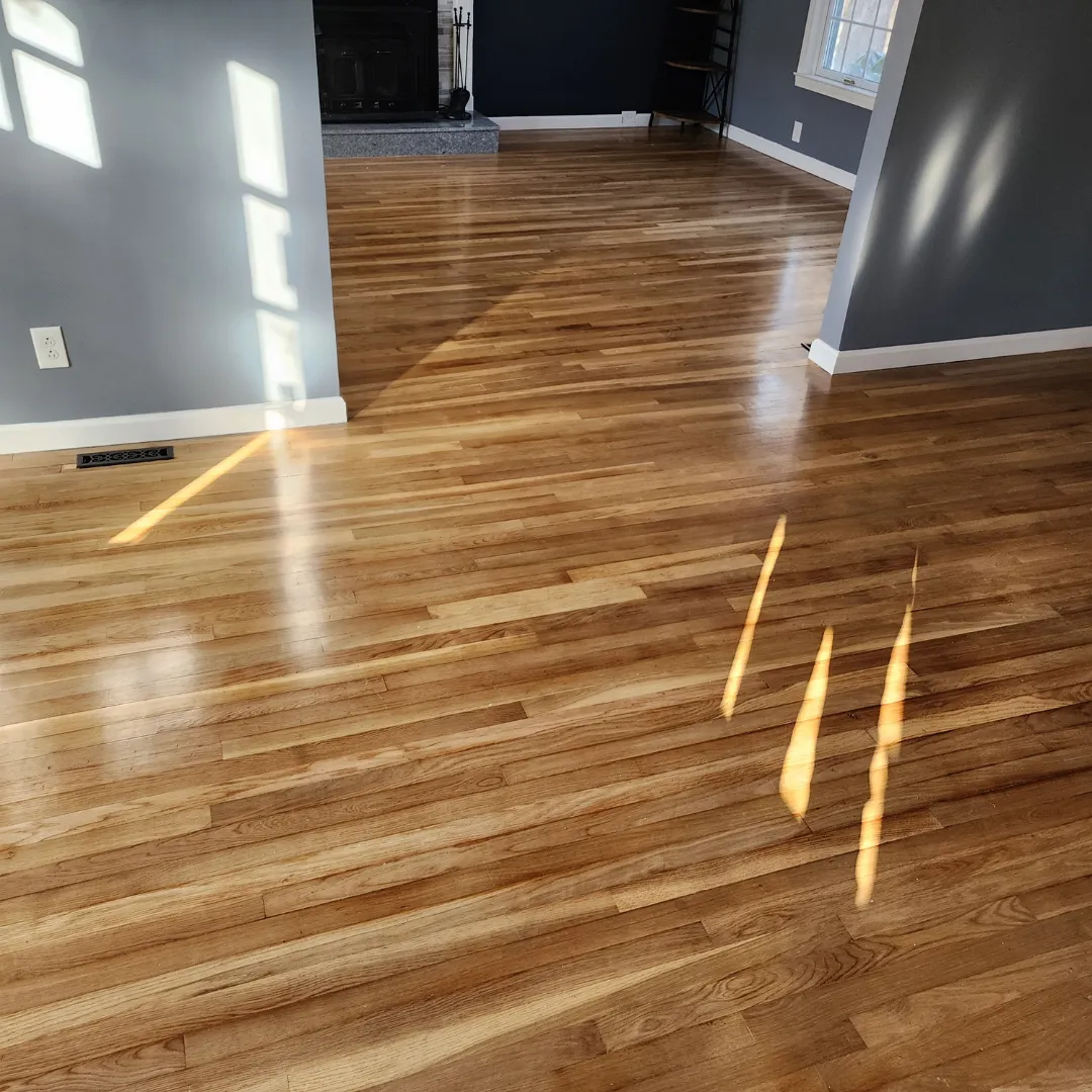 Sun-soaked refinished red oak hardwood floor in open living room by Link Services Pro in Worcester, MA