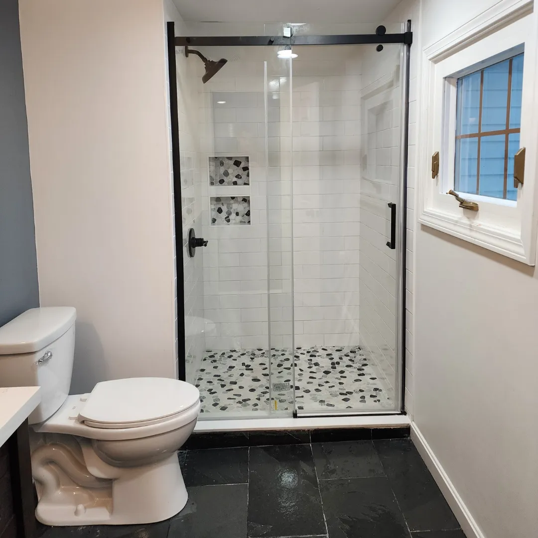Bathroom with frameless glass shower, white subway tile and pebble mosaic floor by Link Services Pro in Auburn, MA