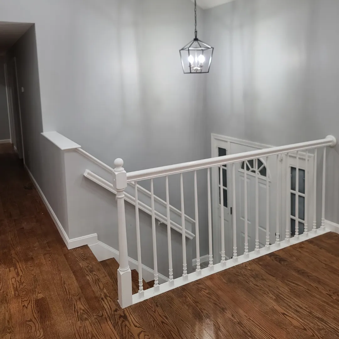 White painted staircase railing with turned newel and refinished oak treads by Link Services Pro in Westborough, MA