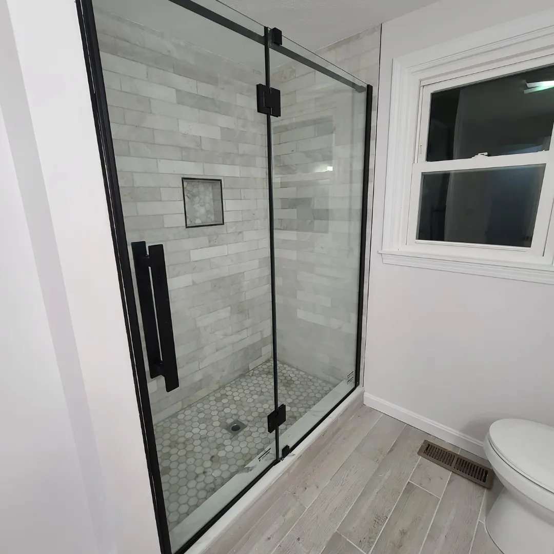 Marble subway tile shower with matte black framed glass enclosure by Link Services Pro in Worcester, MA