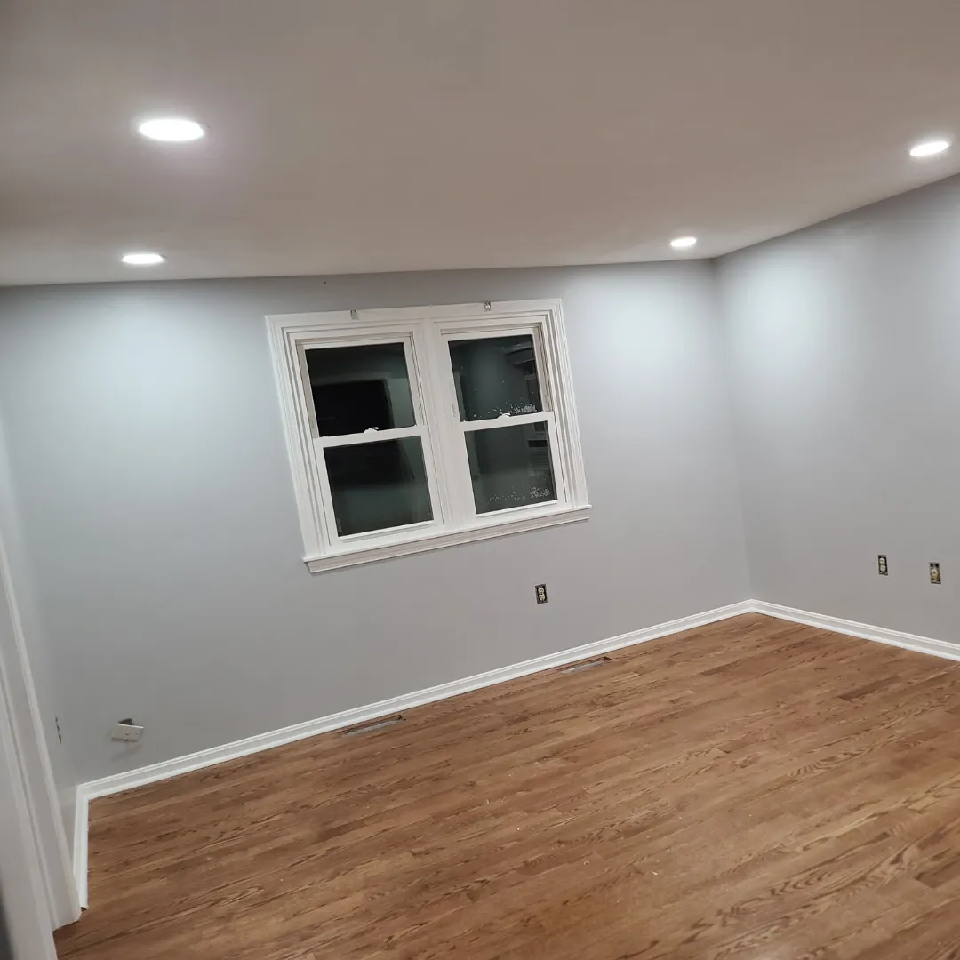 Bedroom with light gray walls, white trim and refinished red oak floor by Link Services Pro in Westborough, MA