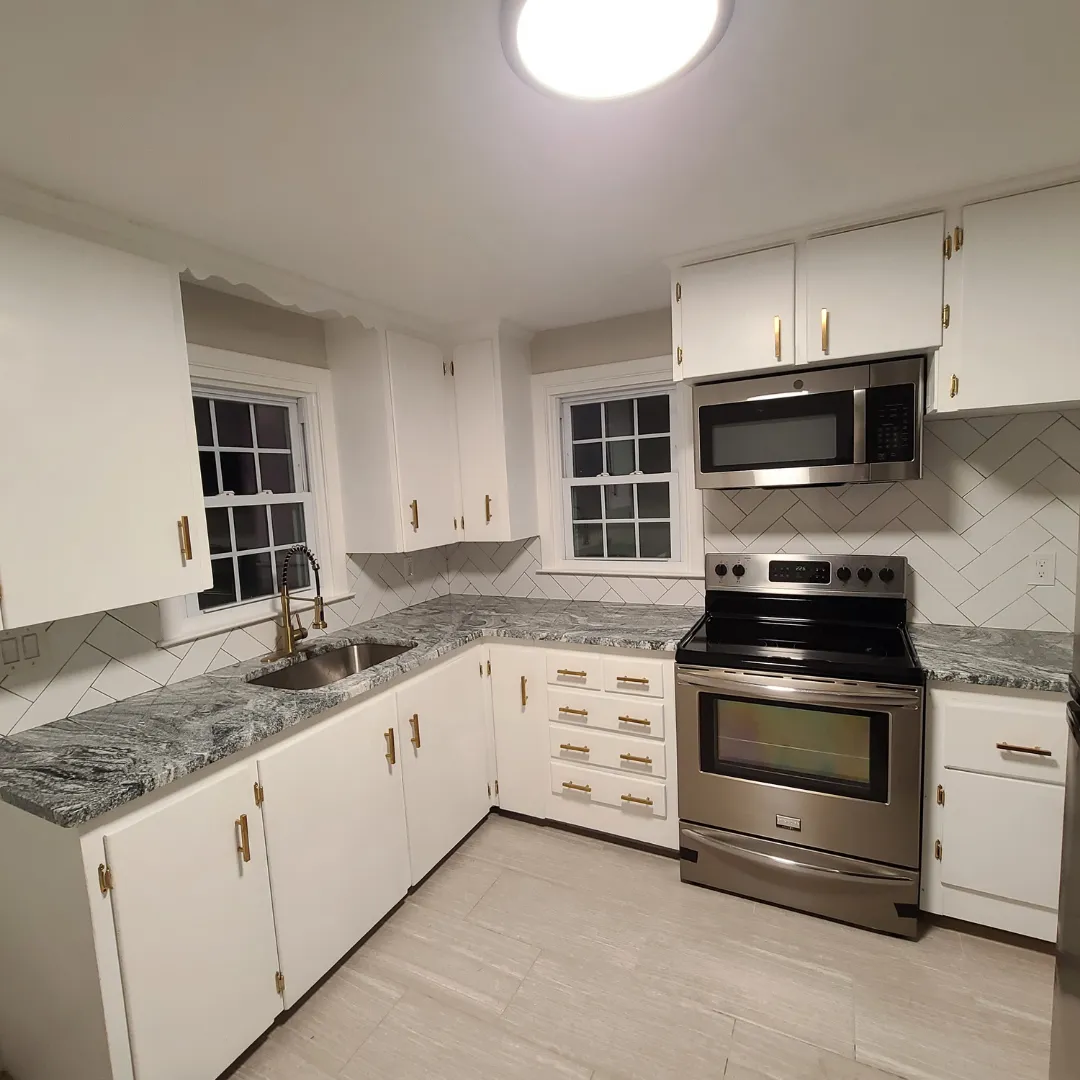 White cabinet kitchen with herringbone subway backsplash and dark granite by Link Services Pro in Millbury, MA