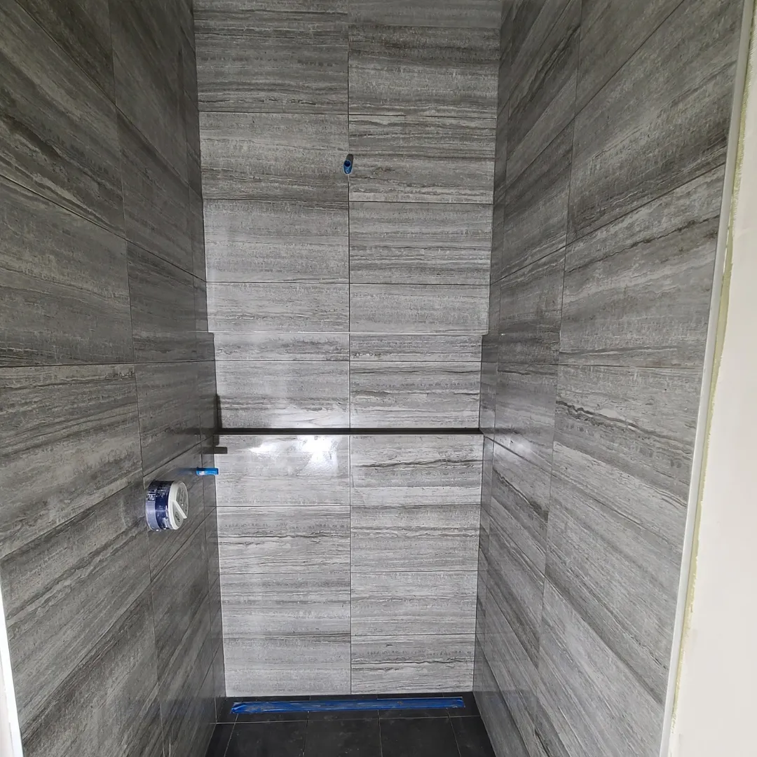 Gray wood-grain porcelain tile shower walls with built-in niche by Link Services Pro in Westborough, MA