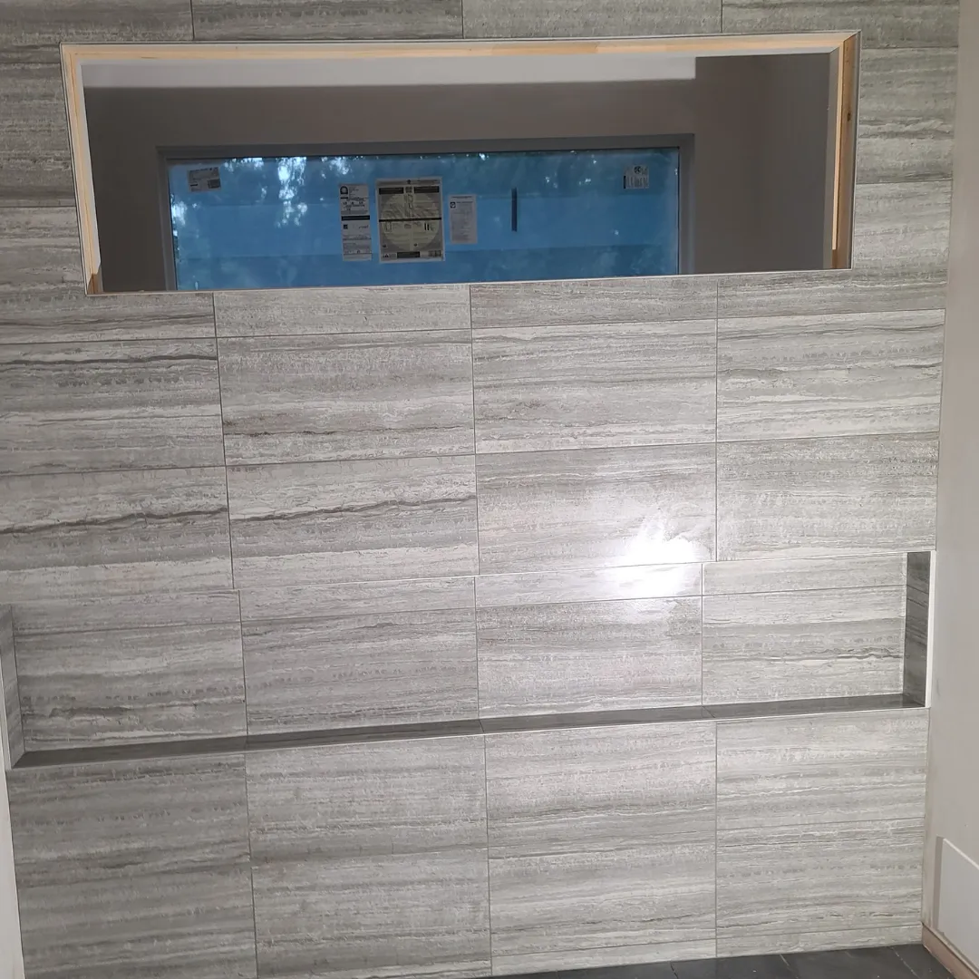 Gray wood-grain porcelain accent wall with built-in shower window niche by Link Services Pro in Holden, MA