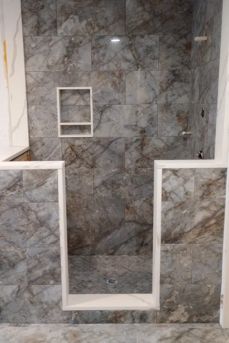 Large-format gray marble-look tile shower surround with niche and curb by Link Services Pro in Shrewsbury, MA