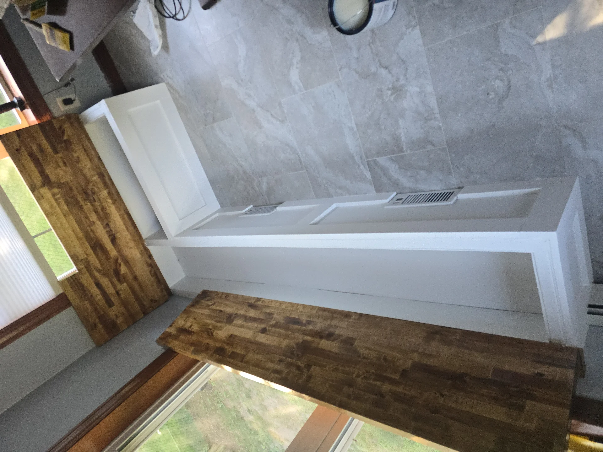 White cabinets being installed next to a large window with wood paneling. by Link Services Pro Inc in Westborough, MA